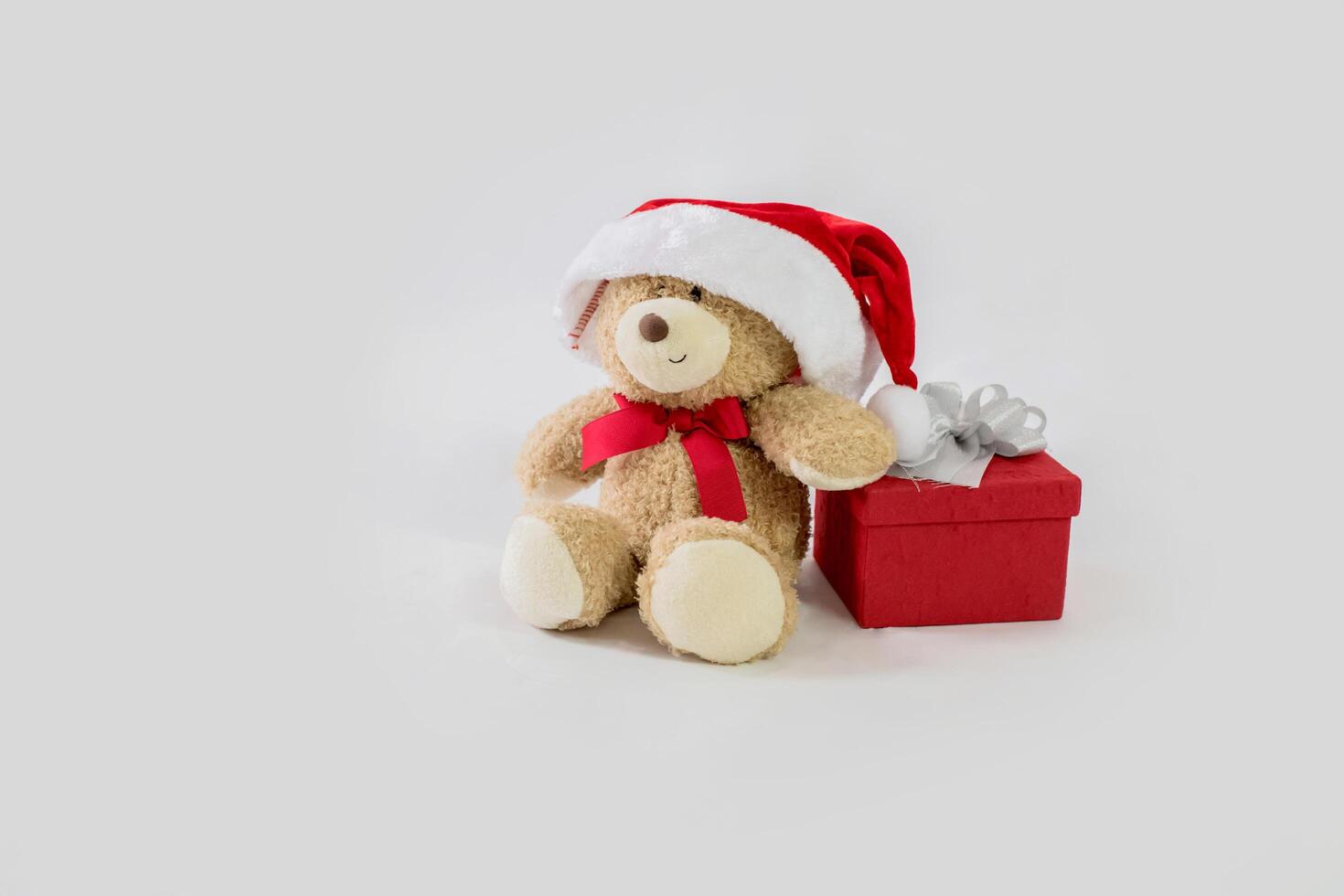 A teddy bear with a santa hat and a gift box photo