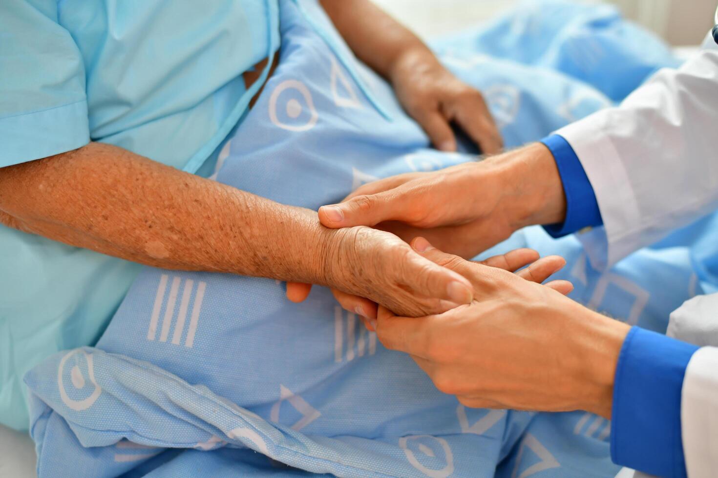 A doctor is holding the hand of an elderly person photo
