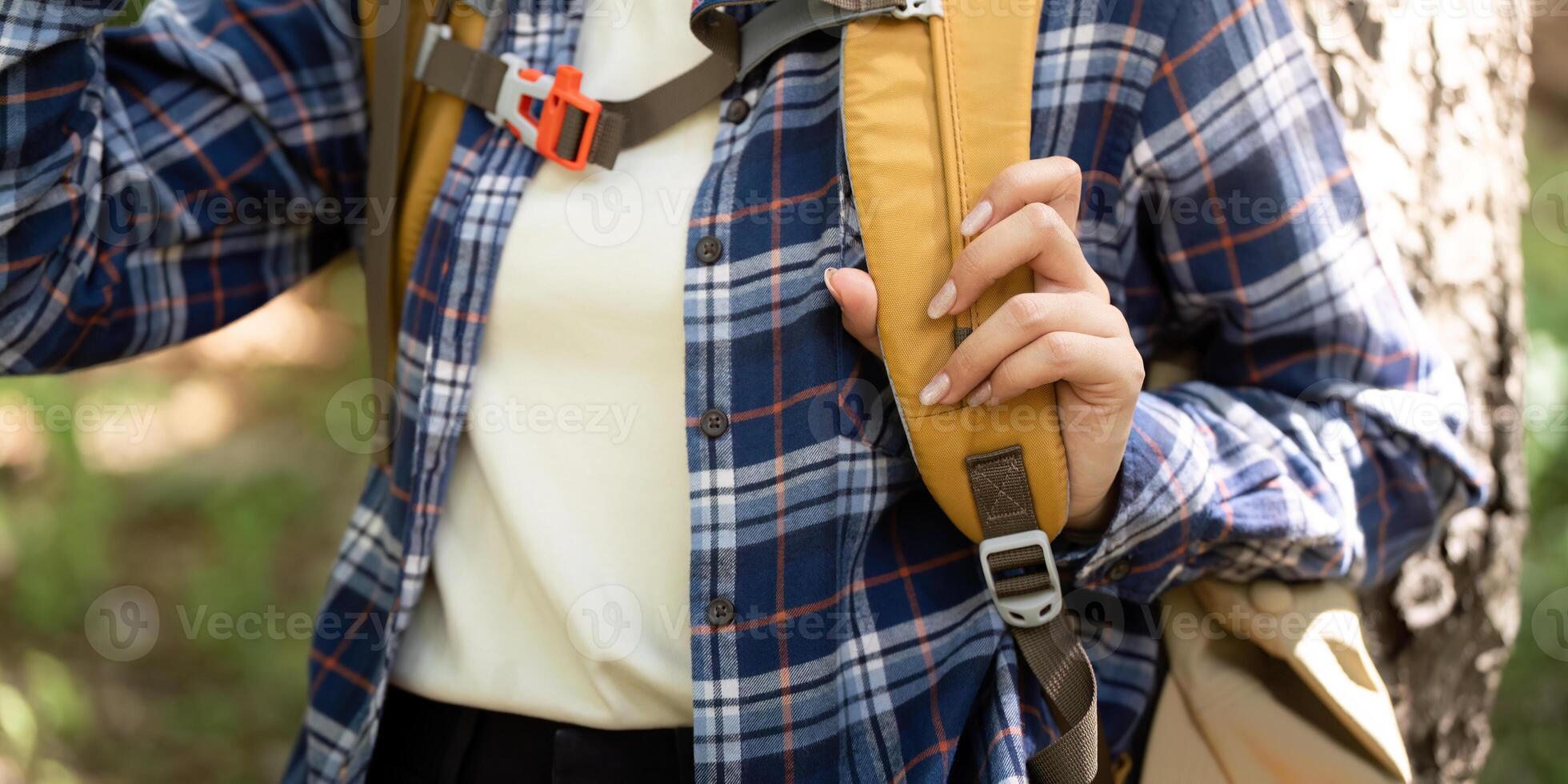 Outdoor Adventure. Young woman adjusting backpack straps in nature. photo