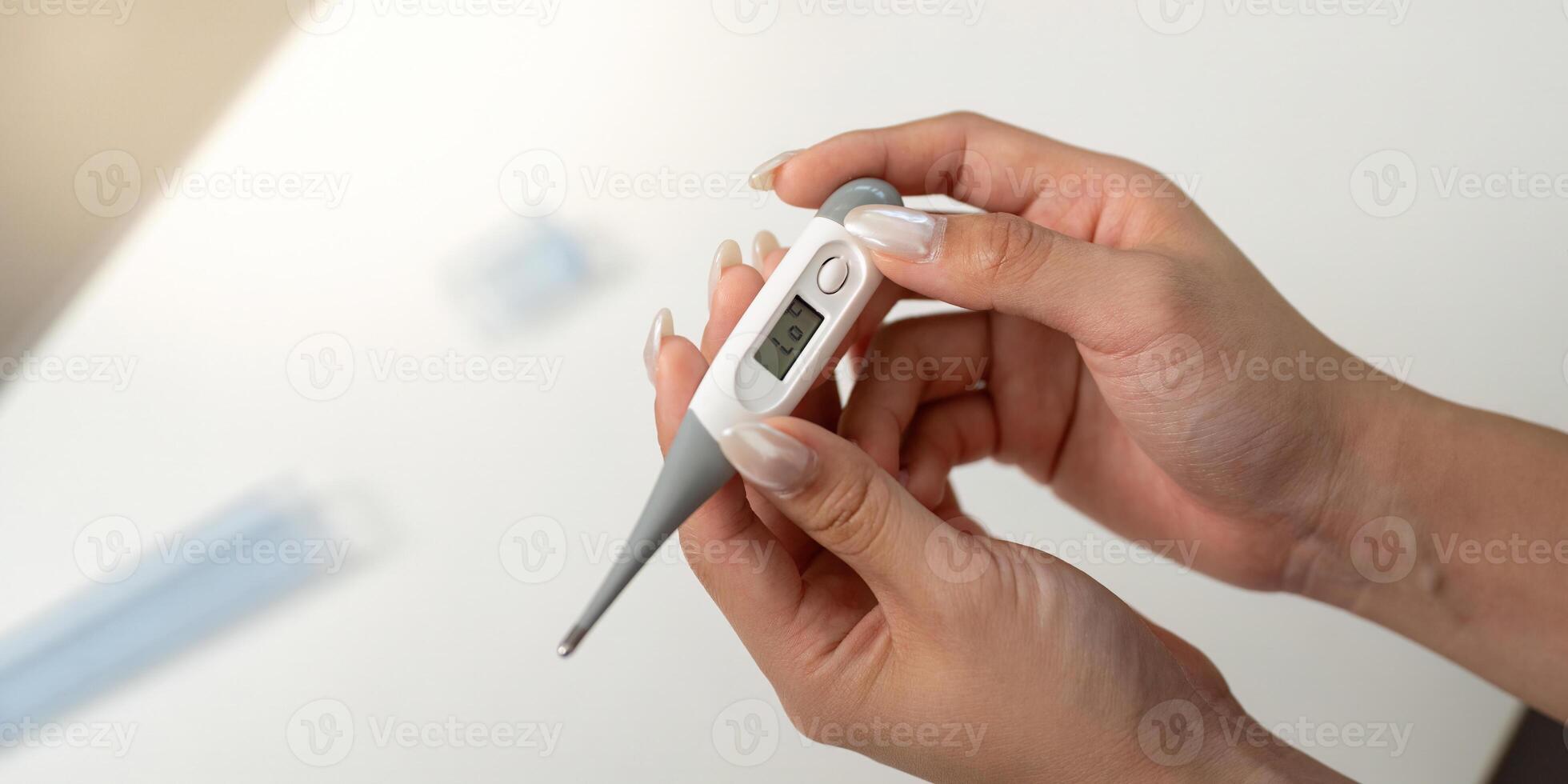 Health Monitoring. Woman checking temperature with digital thermometer at home. photo