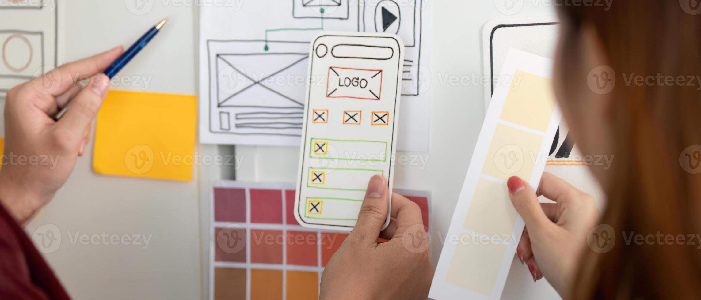 UX and UI Design. Hands holding design mockups and color palettes for mobile app. photo
