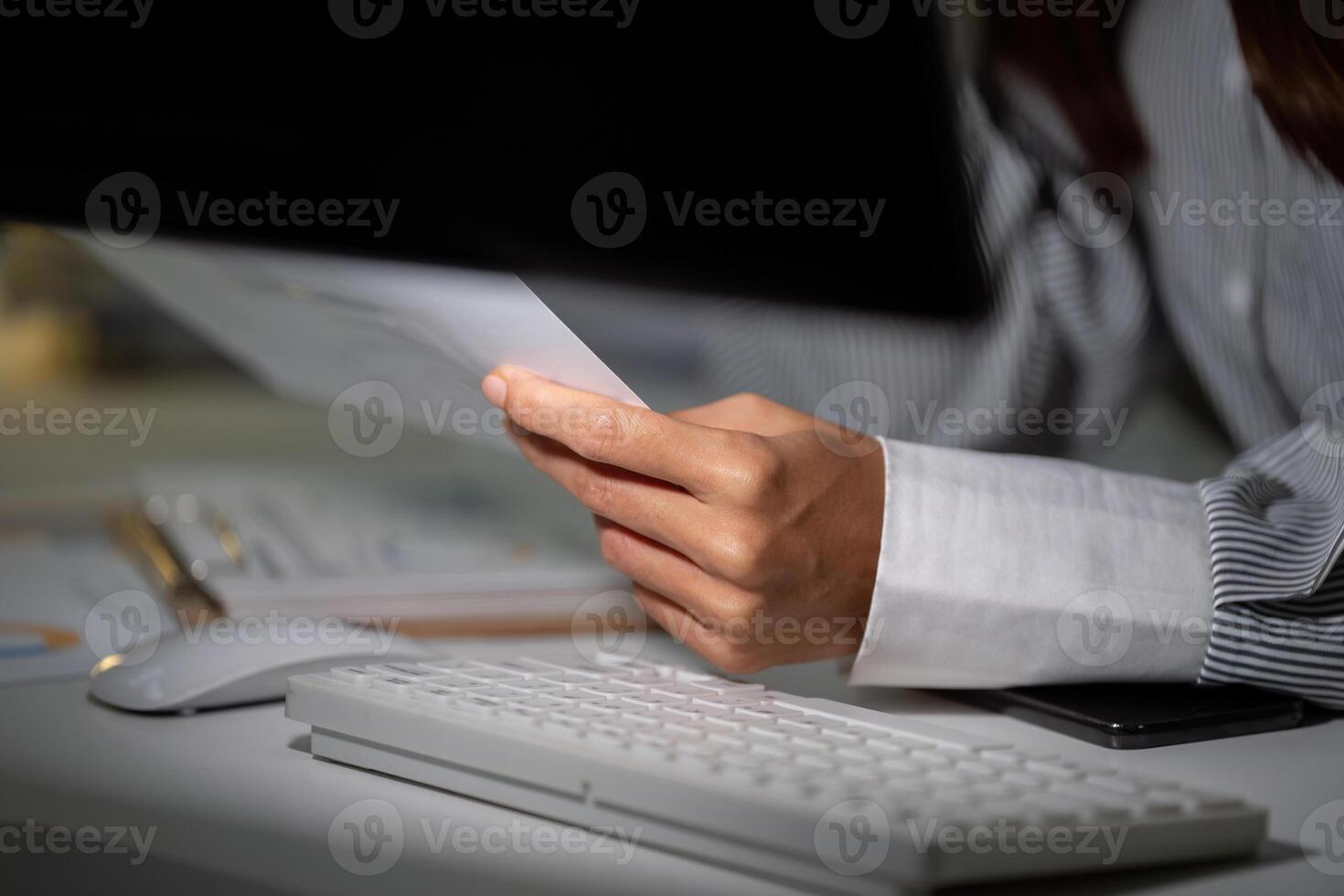 Late Night Focus. Close-up of woman holding document in office setting. photo