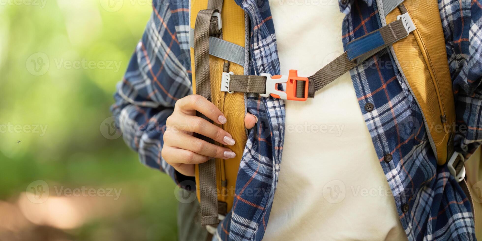 Nature Exploration. Woman fastening backpack straps in the forest. photo