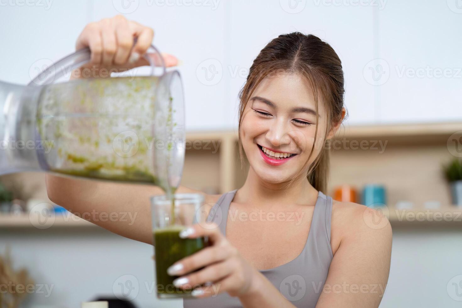 Woman pouring green smoothie into glass photo