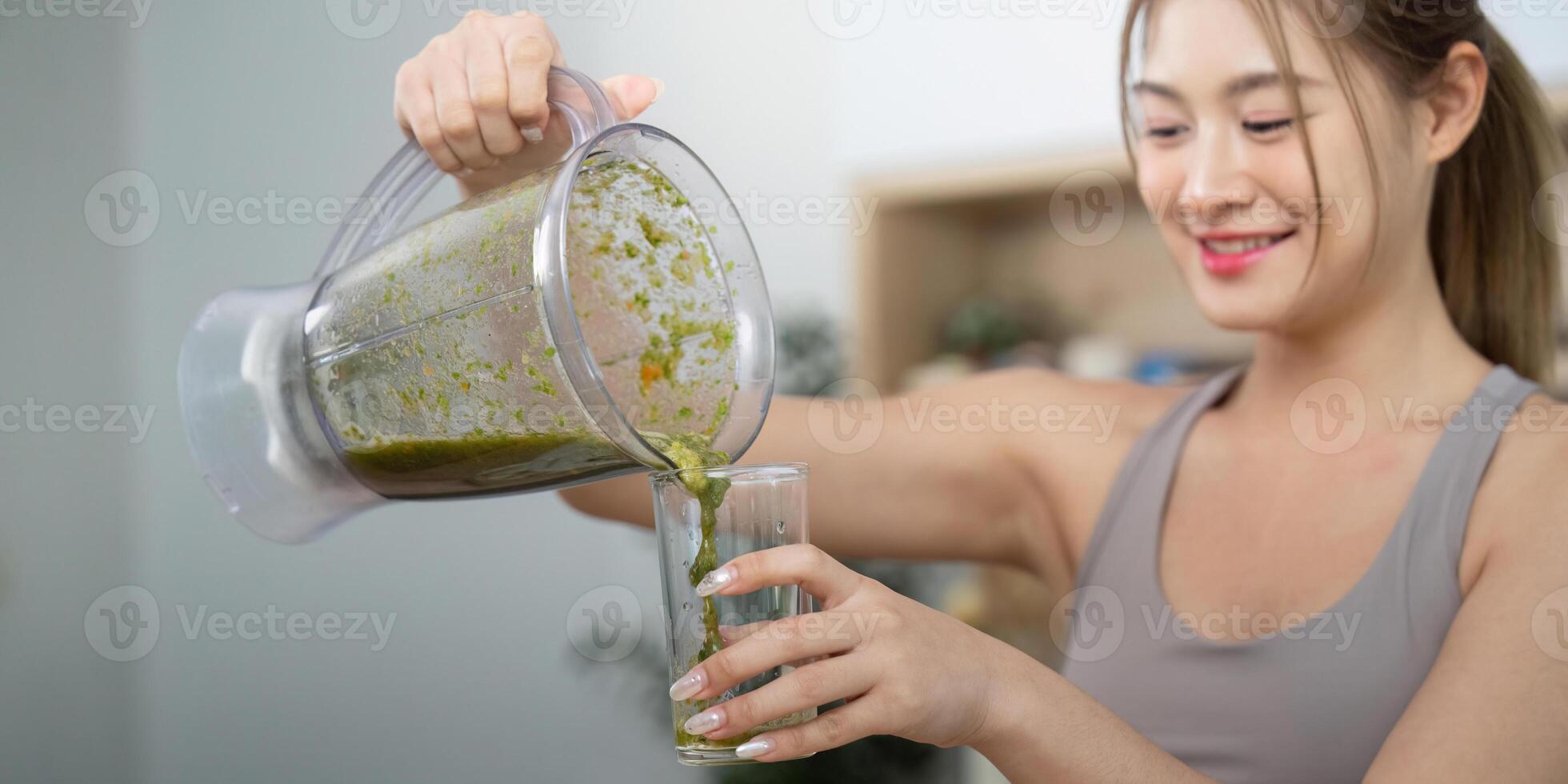Woman pouring green smoothie into glass photo