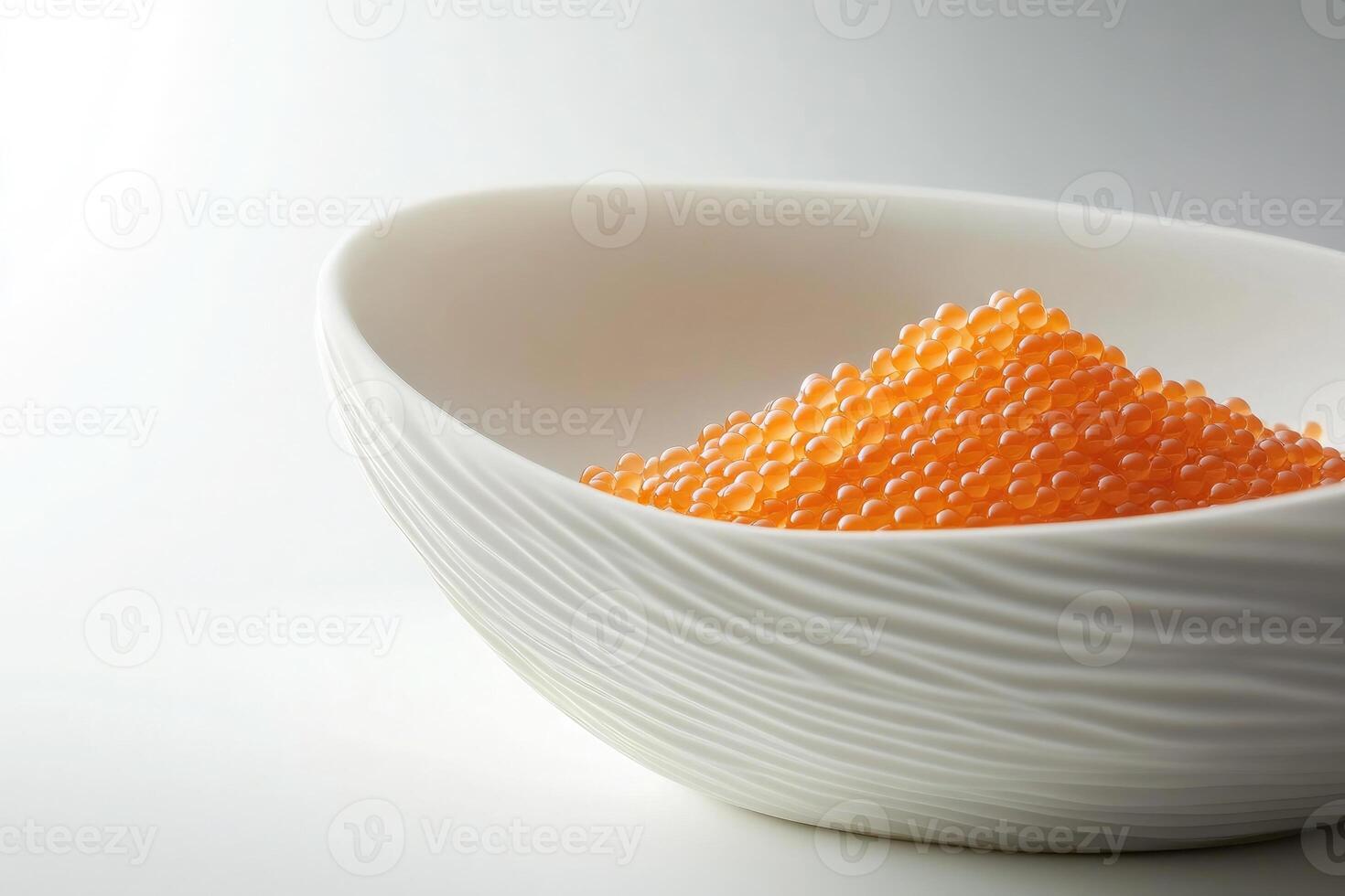 A white bowl filled with orange fish roe. The roe is small, round, and glossy, creating a vibrant contrast against the smooth surface of the bowl. photo