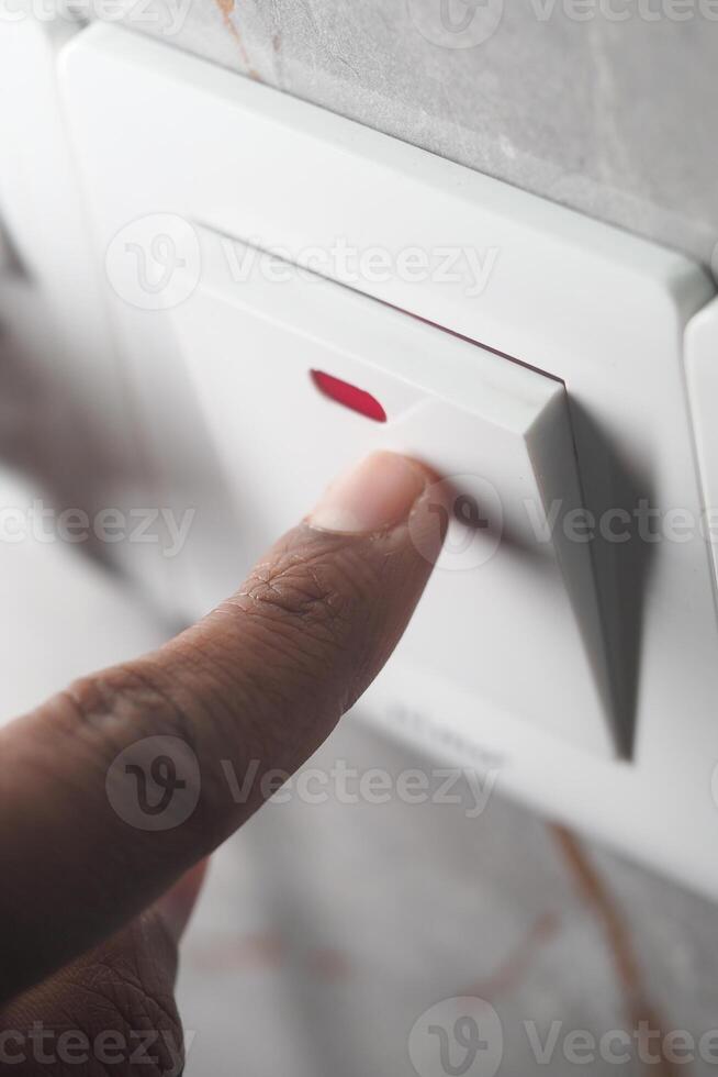 Finger pressing light switch in modern interior setting photo