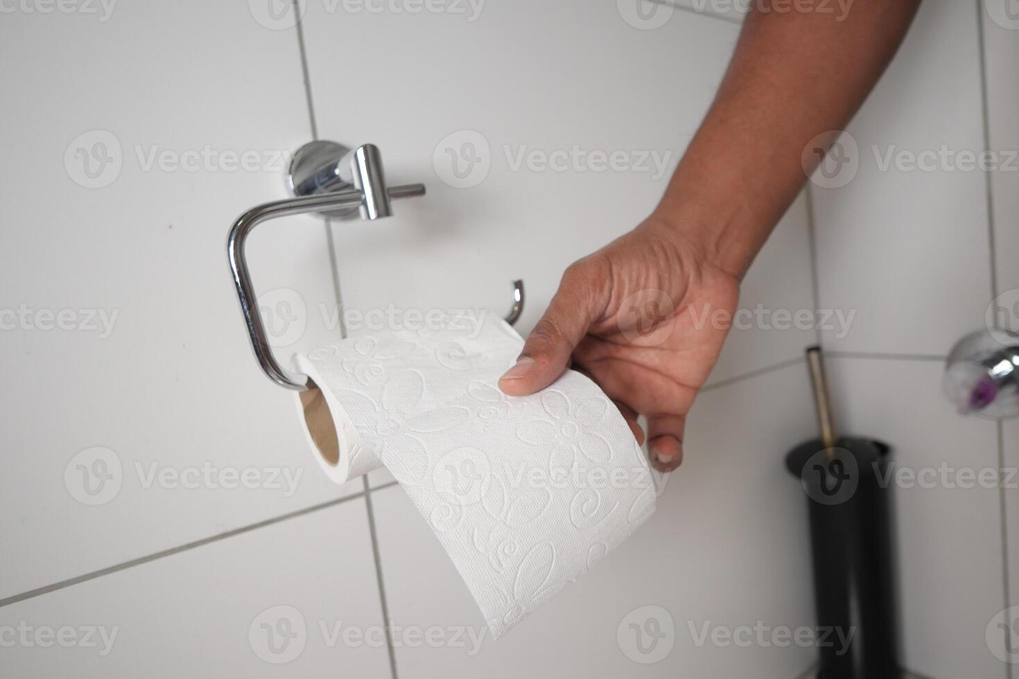 Hand reaching for toilet paper in a bathroom setting photo