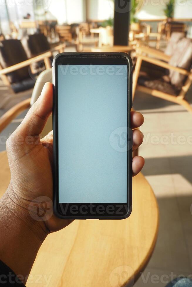 Hand holding smartphone in a cozy indoor setting photo