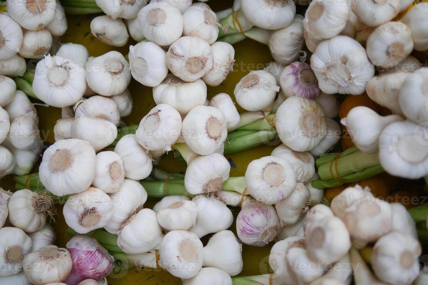 Fresh garlic bulbs stacked for sale at a market stand photo