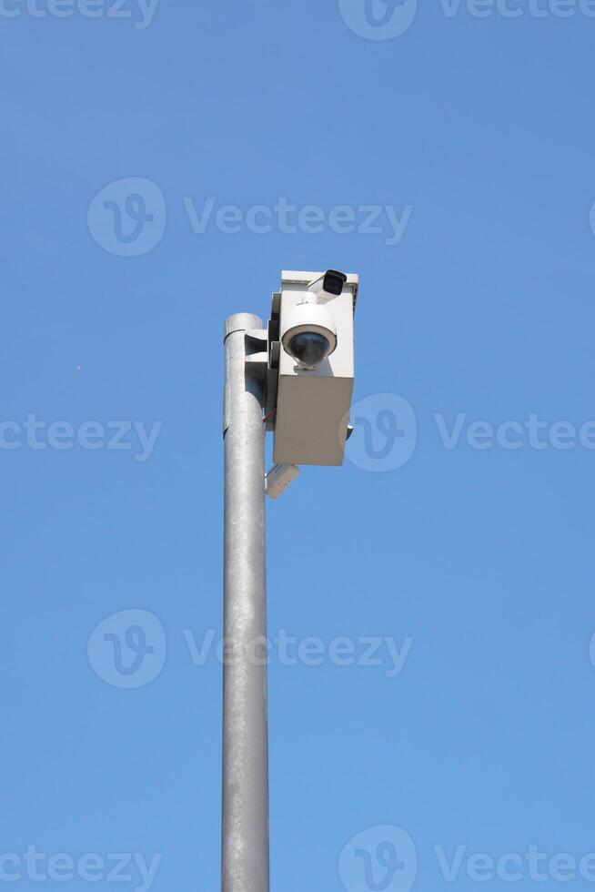 Security camera mounted on pole against clear blue sky photo