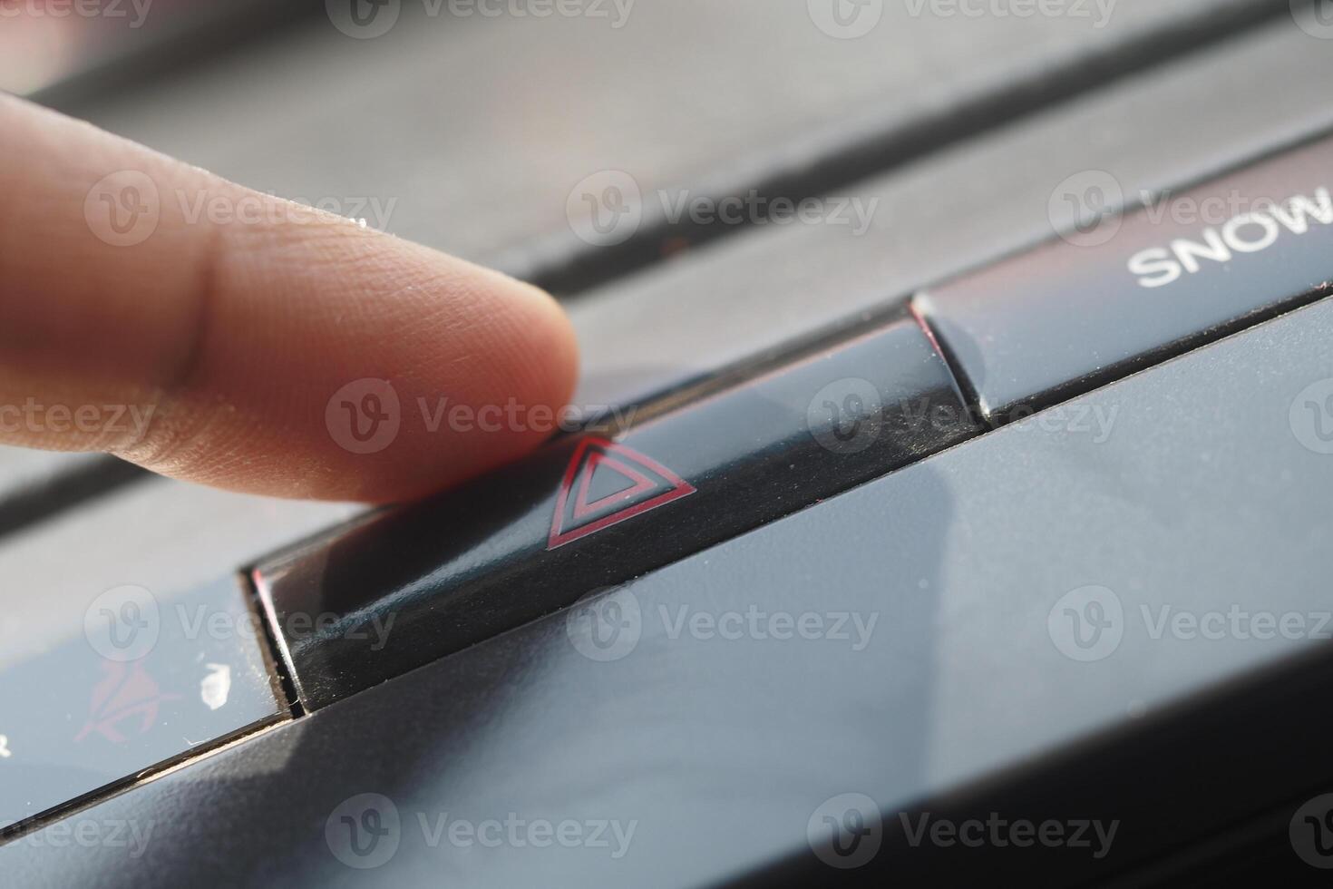 Finger pressing hazard light button inside vehicle photo