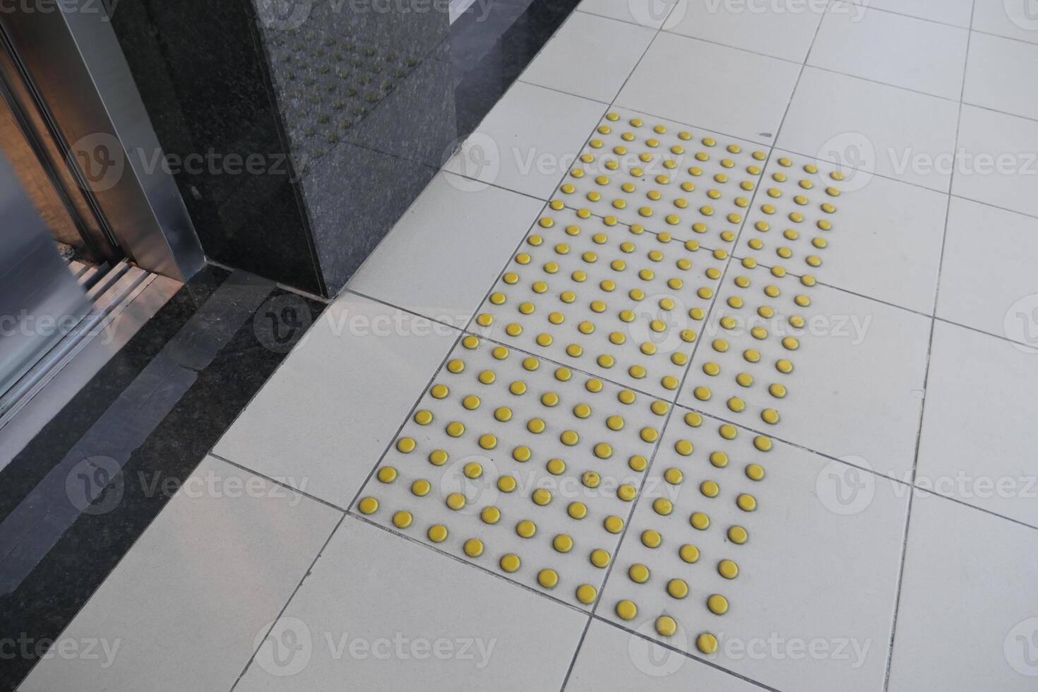 Yellow tactile ground indicators near elevator entrance photo