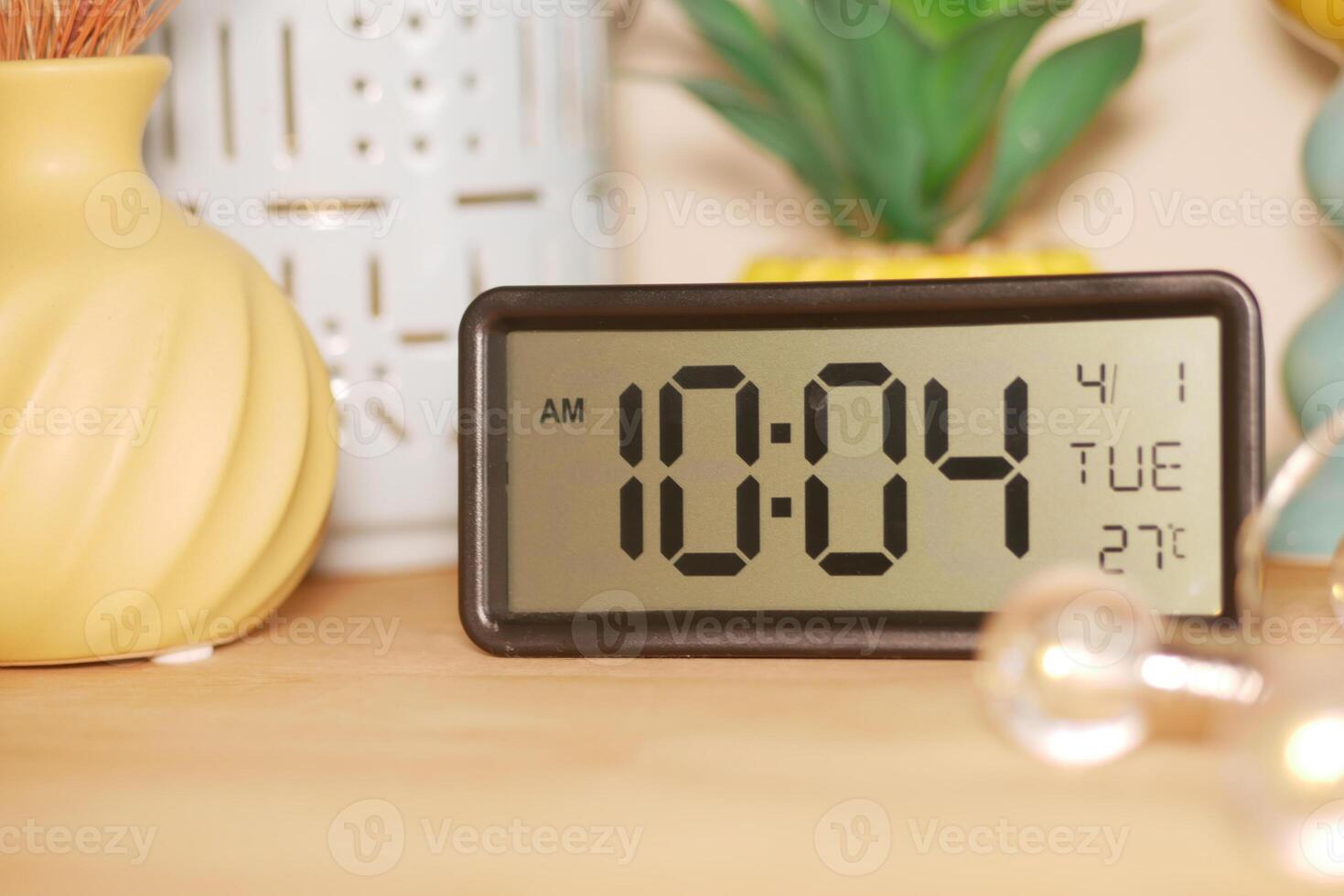 A digital clock shows 10.04 AM on a Tuesday in a warm room photo