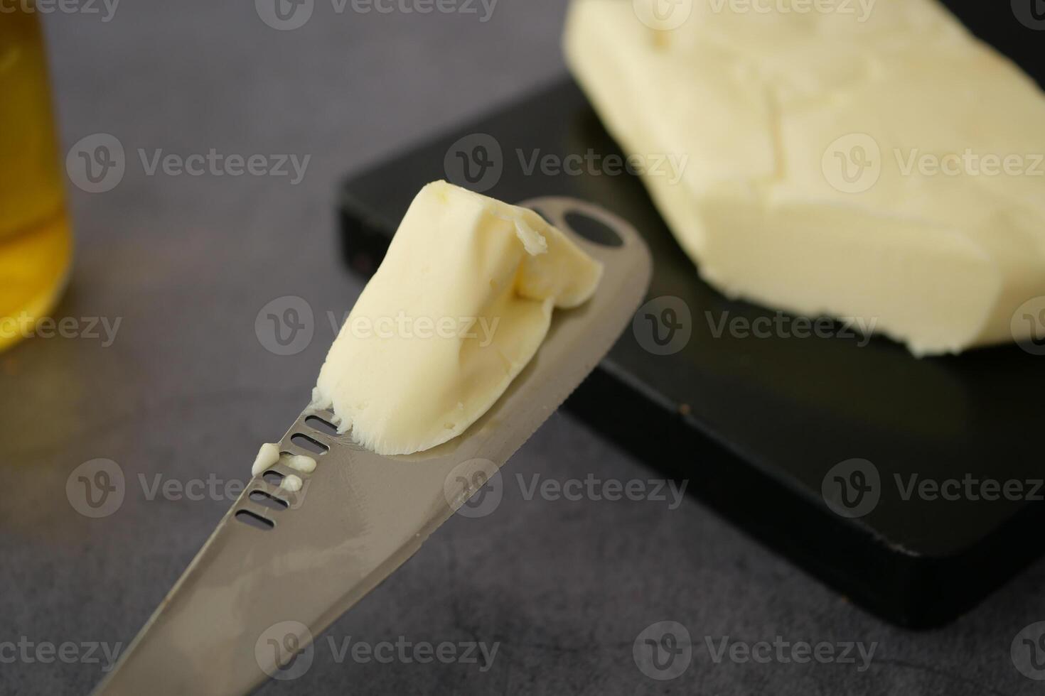 Butter being spread with a knife on a dark cutting board photo