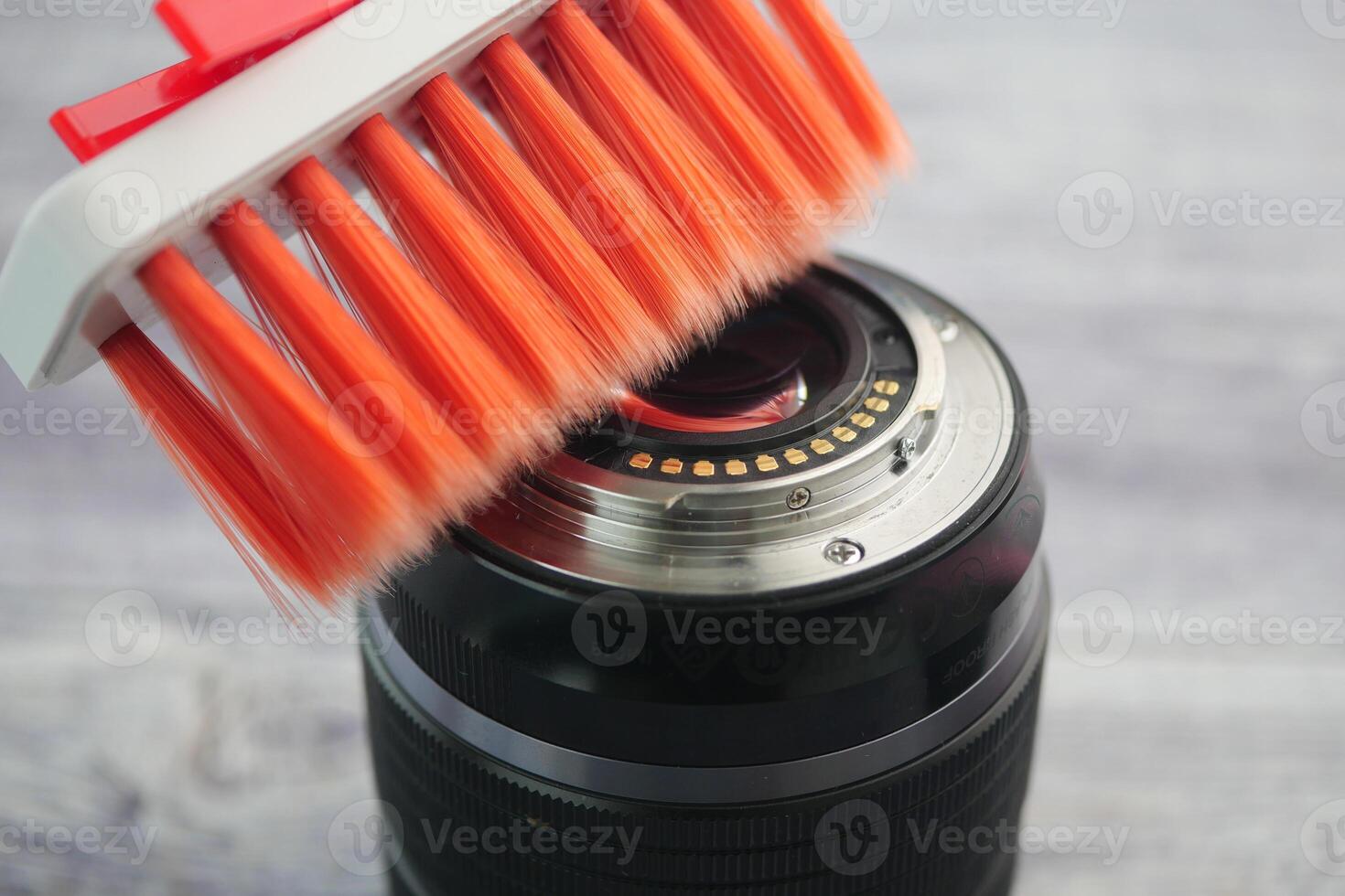 Camera lens cleaning with a brush on a wooden surface photo