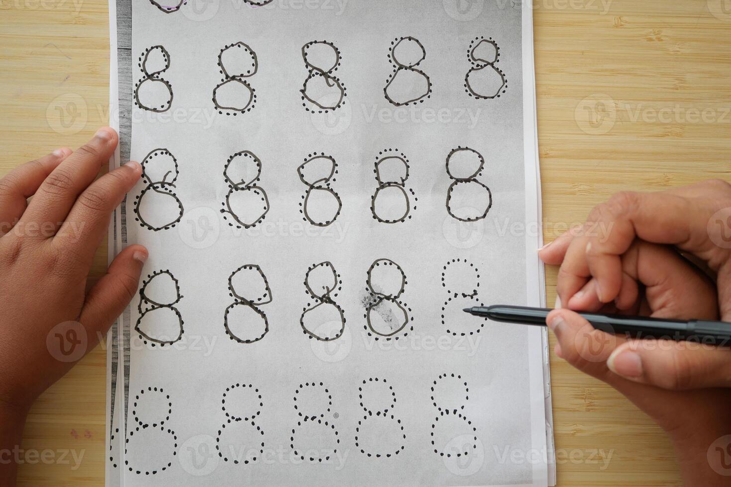 Child practicing number eight writing with dotted lines photo