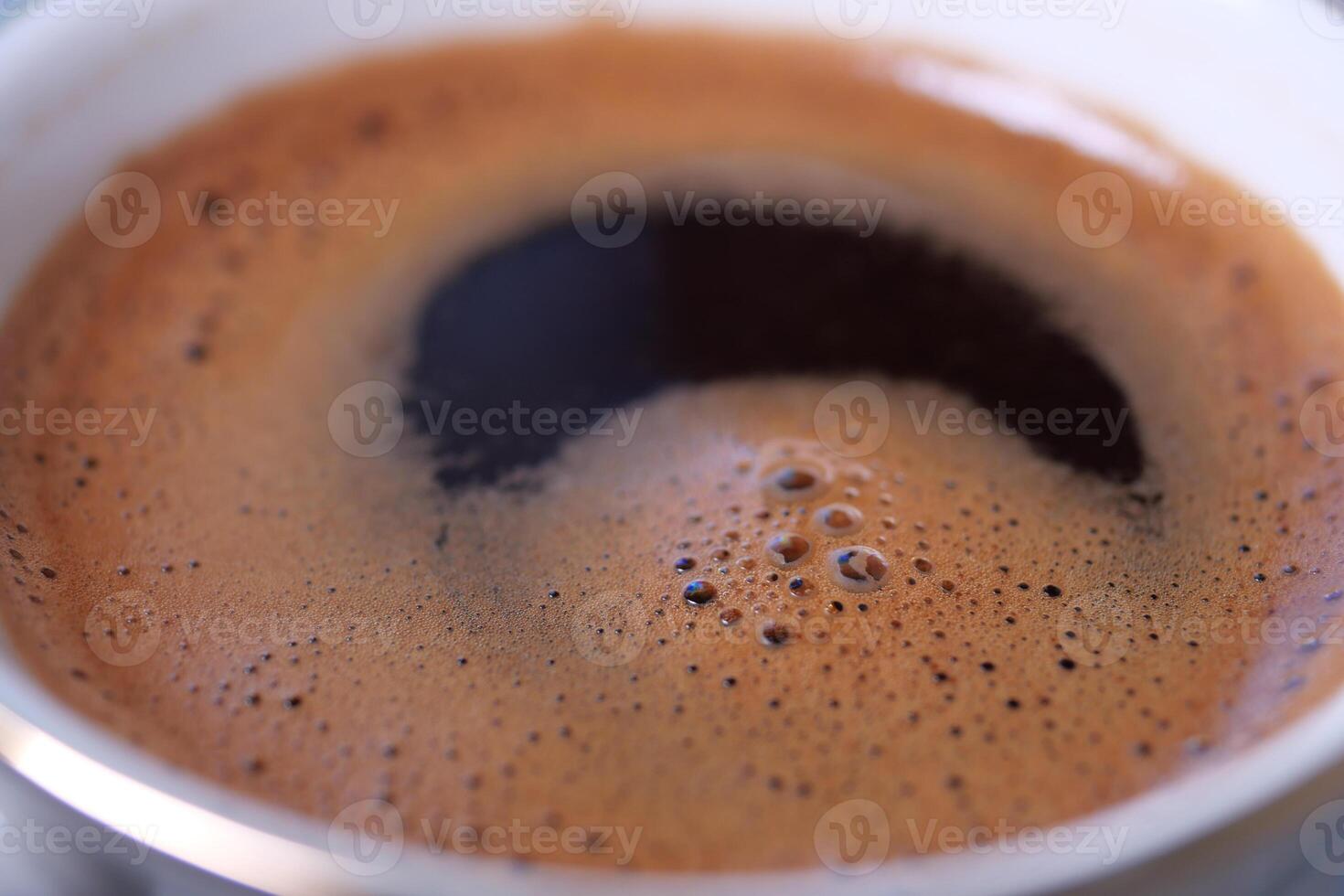 Dark, rich coffee brew in a cup with foamy surface photo