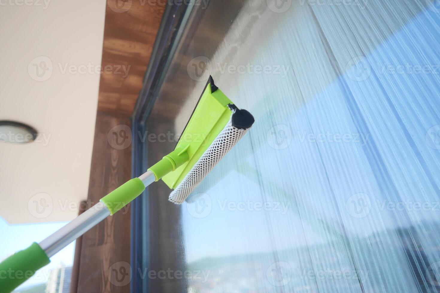 Cleaning glass surfaces with a green squeegee tool photo