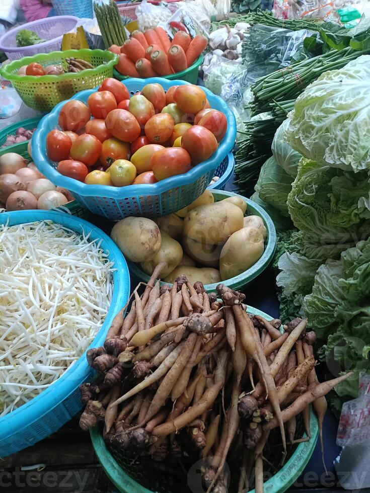 Fresh vegetables and fruits displayed at market stall, including tomatoes, potatoes, bean sprouts, ginger, and leafy greens, creating colorful and vibrant scene full of healthy produce photo