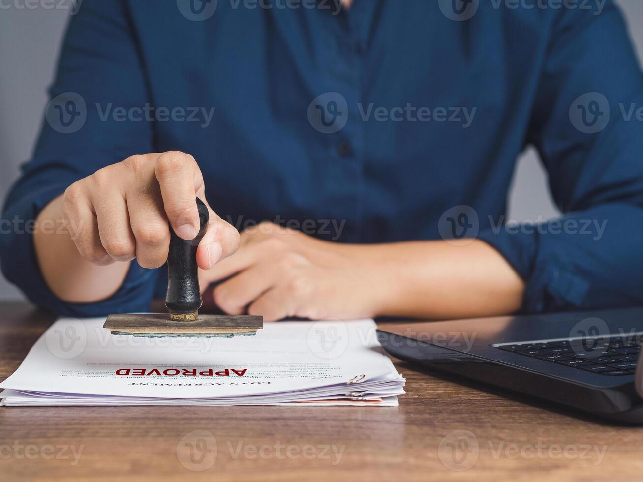 Businesswoman stamped approved on a document while sitting in the office photo