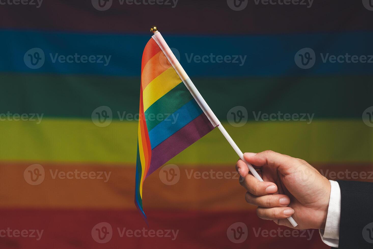 Rainbow flag in hand against a rainbow flag background photo