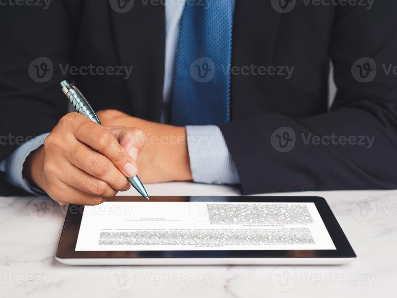 Signature electronic. Businessman signing a digital contract or agreement on a tablet while sitting in the office photo