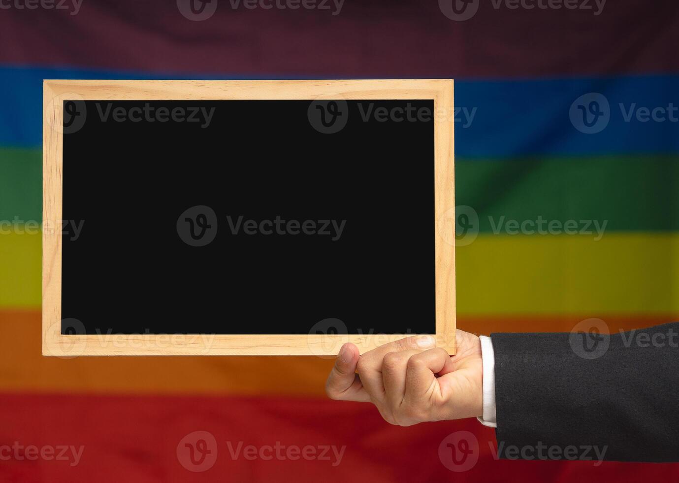 Hand holding a mini black chalkboard against a rainbow flag or LGBT flag background photo