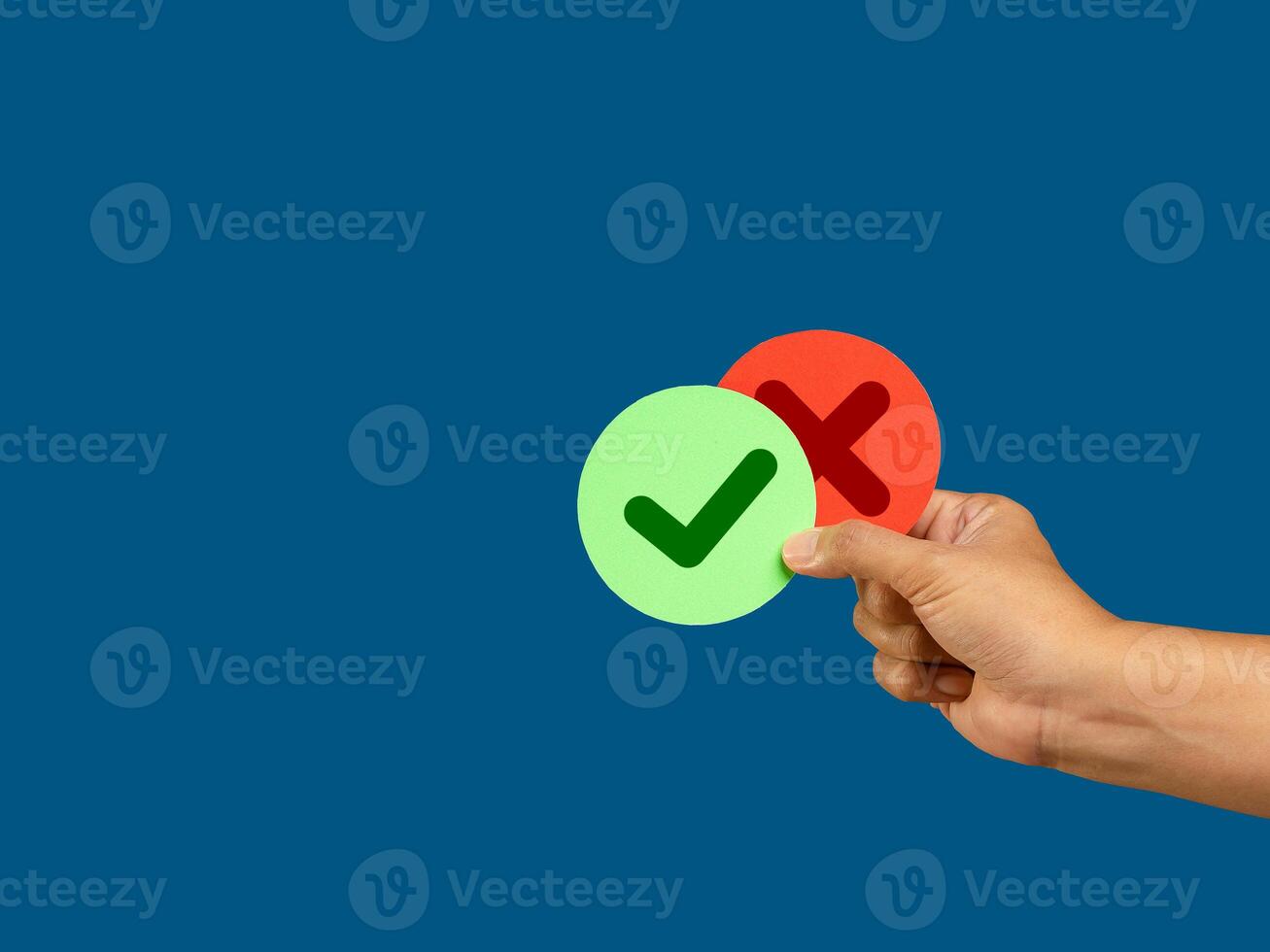 Hand holding two pieces of paper green and red with a checkmark and cross photo