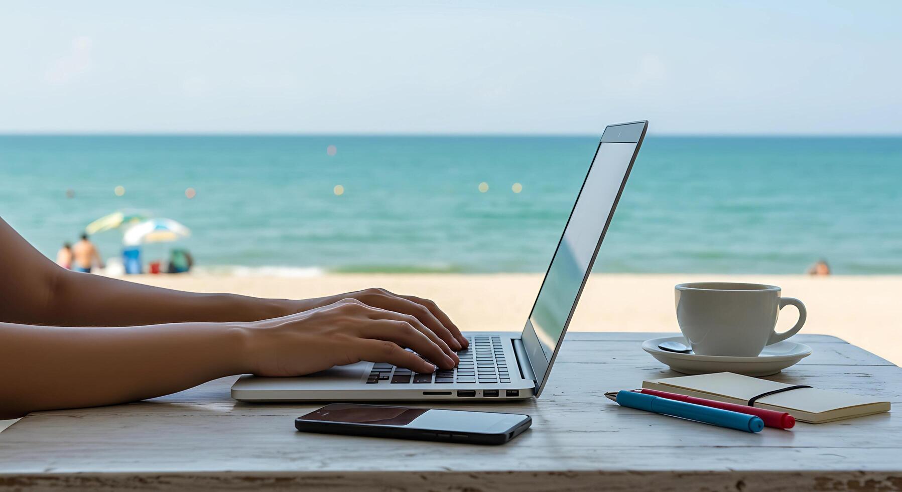 digital nomad working on a laptop at a beach cafe. with a laptop and coffee photo