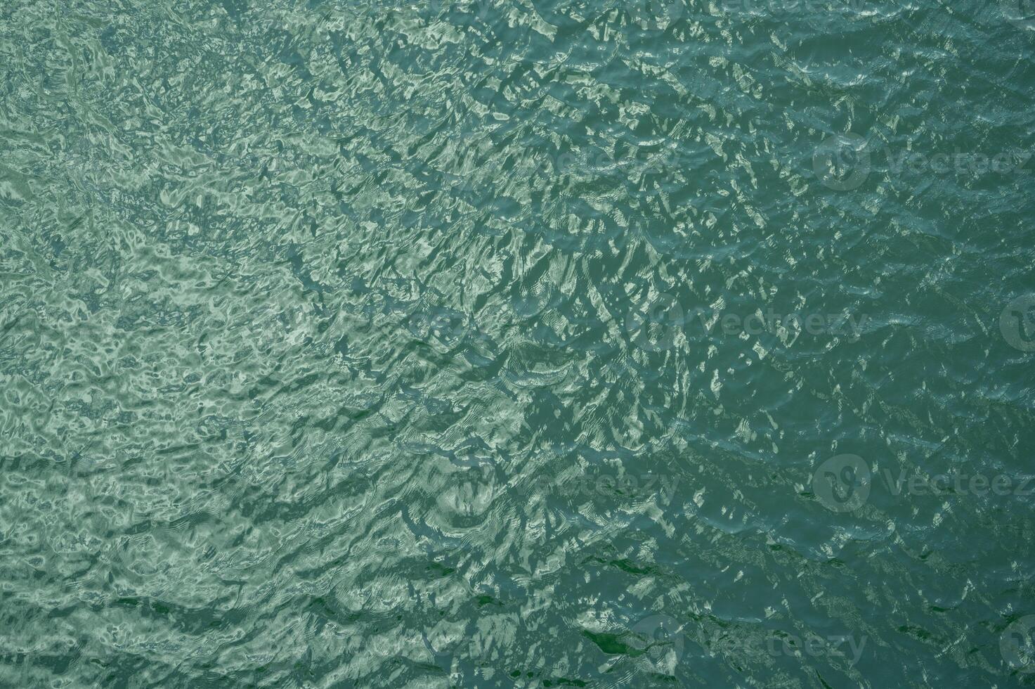 Top view of calm water surface texture with soft natural ripples. Background for eco-friendly design, peaceful concepts, and water sustainability. Blue green lake surface water background. photo