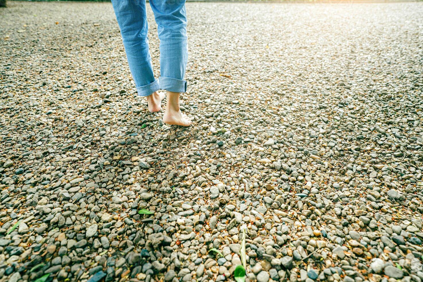 Close-up of barefoot woman walking on gravel ground in a peaceful forest retreat during early morning light. Self-care, emotional healing, and connection with nature for mental balance. Mindfulness. photo