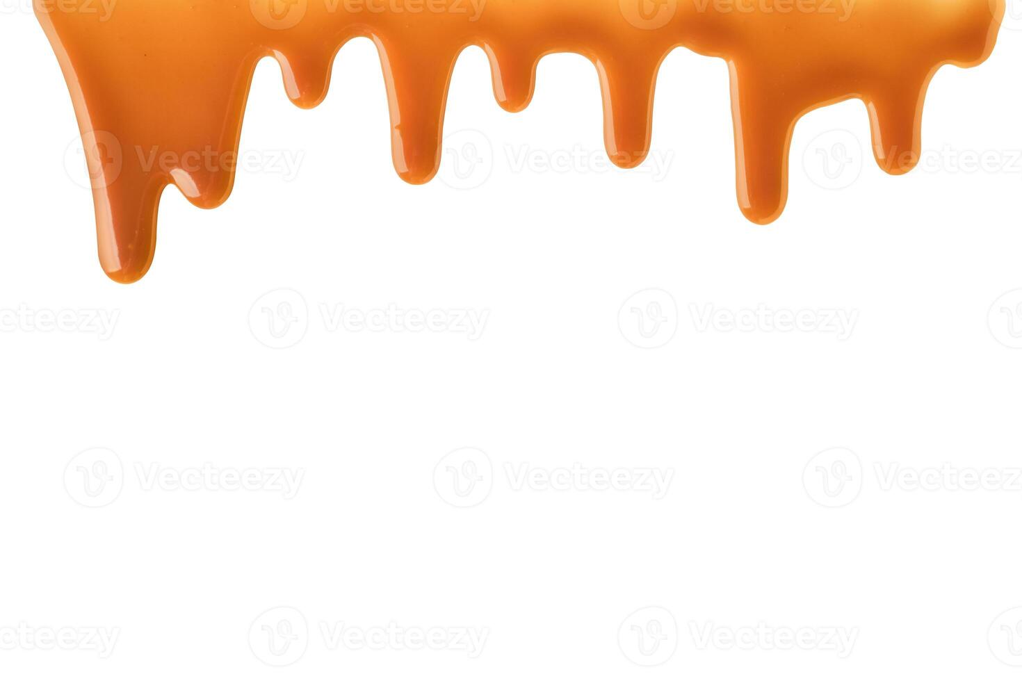 Melted caramel sauce drips down frame on white background photo