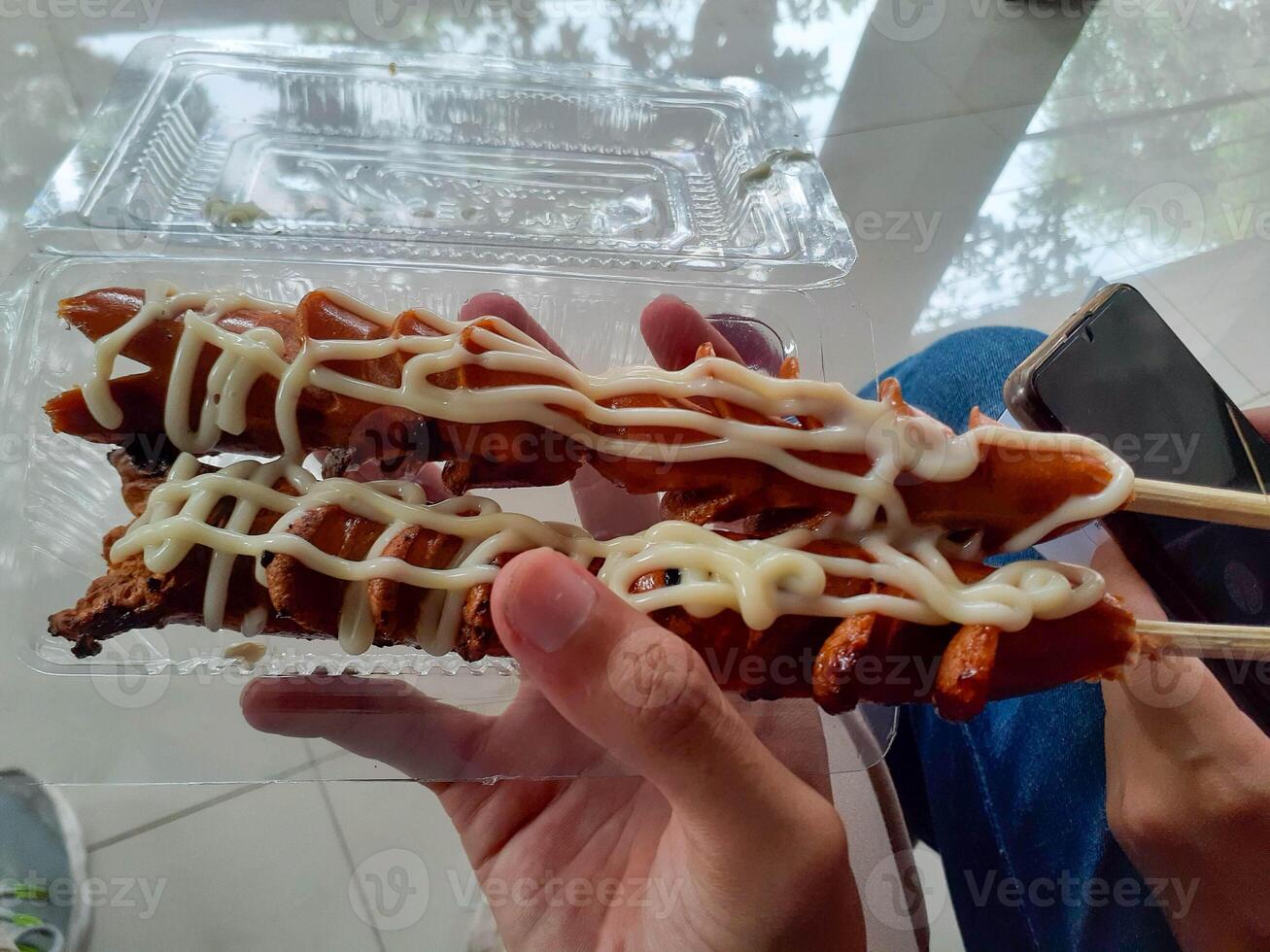 Grilled Sausage Skewers with Mayonnaise Drizzle Held in Hand, Ready to Eat photo
