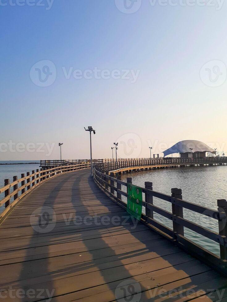 Tranquil Wooden Pier Extends Over Calm Water, Sunrise Shadows Dance photo