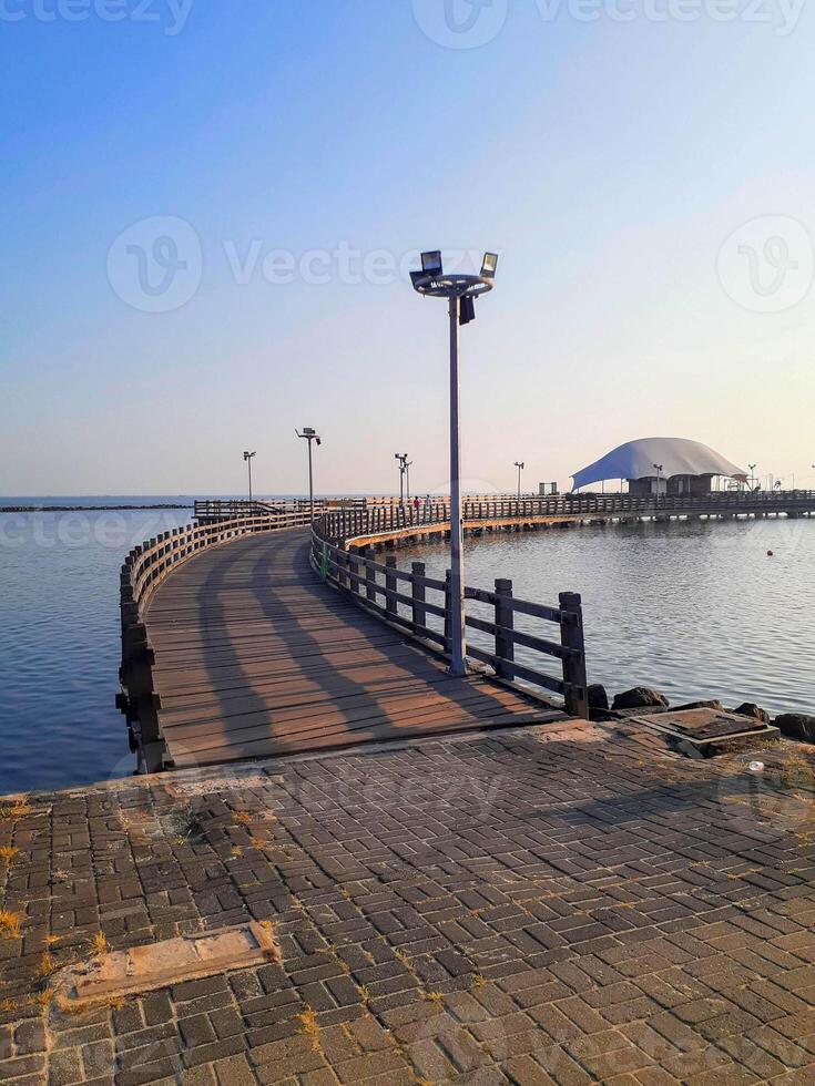 Serene Wooden Pier at Ancol Beach, Jakarta, Indonesia, Under Clear Blue Sky photo