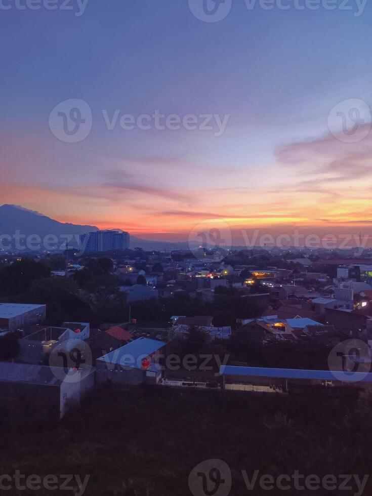 Bandung Cityscape at Dusk Mountains, Buildings, and Vibrant Sky photo