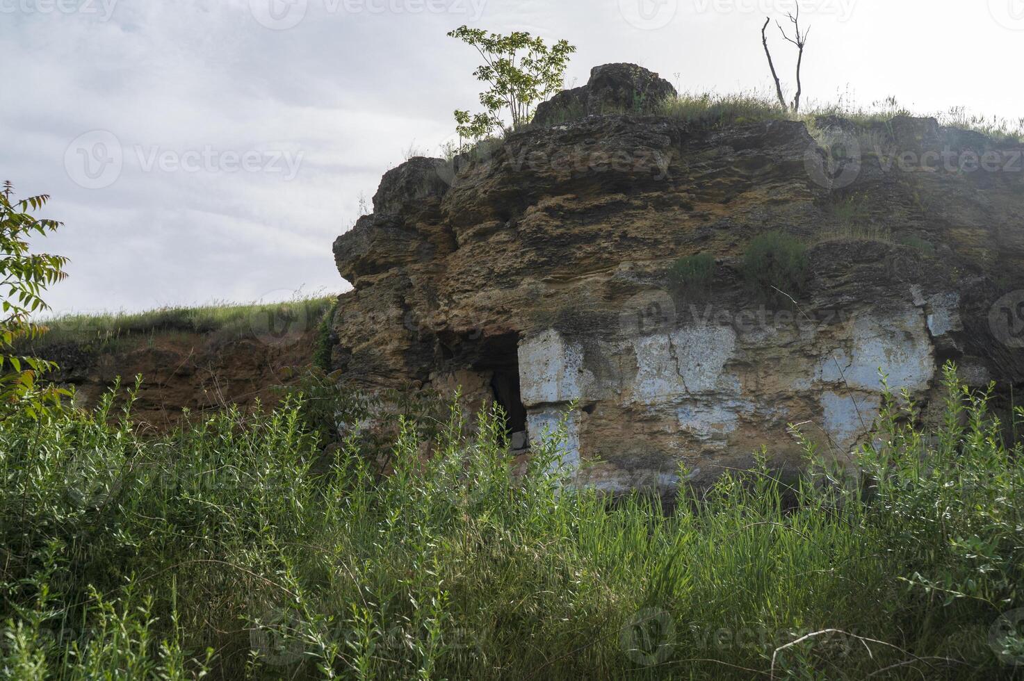 Abandoned cave house in the rock. Cave old city. entrance to the caves. stunning landscape in the haze of the sun. lush greenery around the rock. catacombs in europe. production and quarrying of stone photo