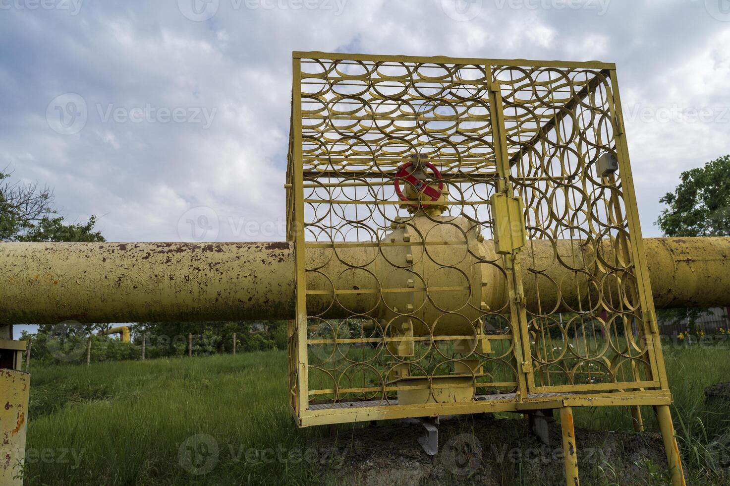 Protective structure of gas pipeline in fenced area on summer day. Part of gas pipeline control point in the middle of field. Industrial installation in open air. Concept of ecological safety photo
