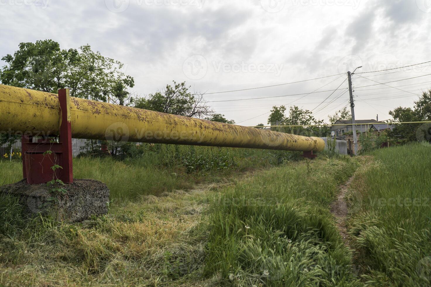 Gas pipe goes across the field. Huge pipe in diameter yellow color against the background of rural landscape. Concept of ecological safety and infrastructure. photo