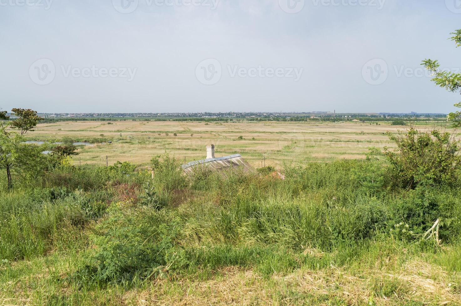 Idyllic view of a beautiful and peaceful farmhouse in the rural flatlands of Europe. A lonely hut in the middle of green fields. A city is visible on the distant horizon. photo