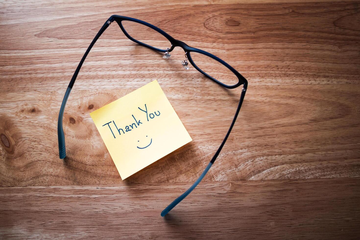 Grateful gesture thank you note with glasses wooden desk personal touch cozy home office close-up view photo