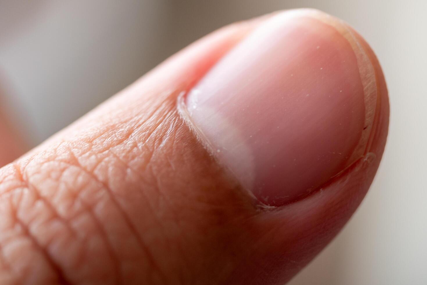 Close-up action of a finger's fingernail indoor setting macro detailed focus skin texture photo