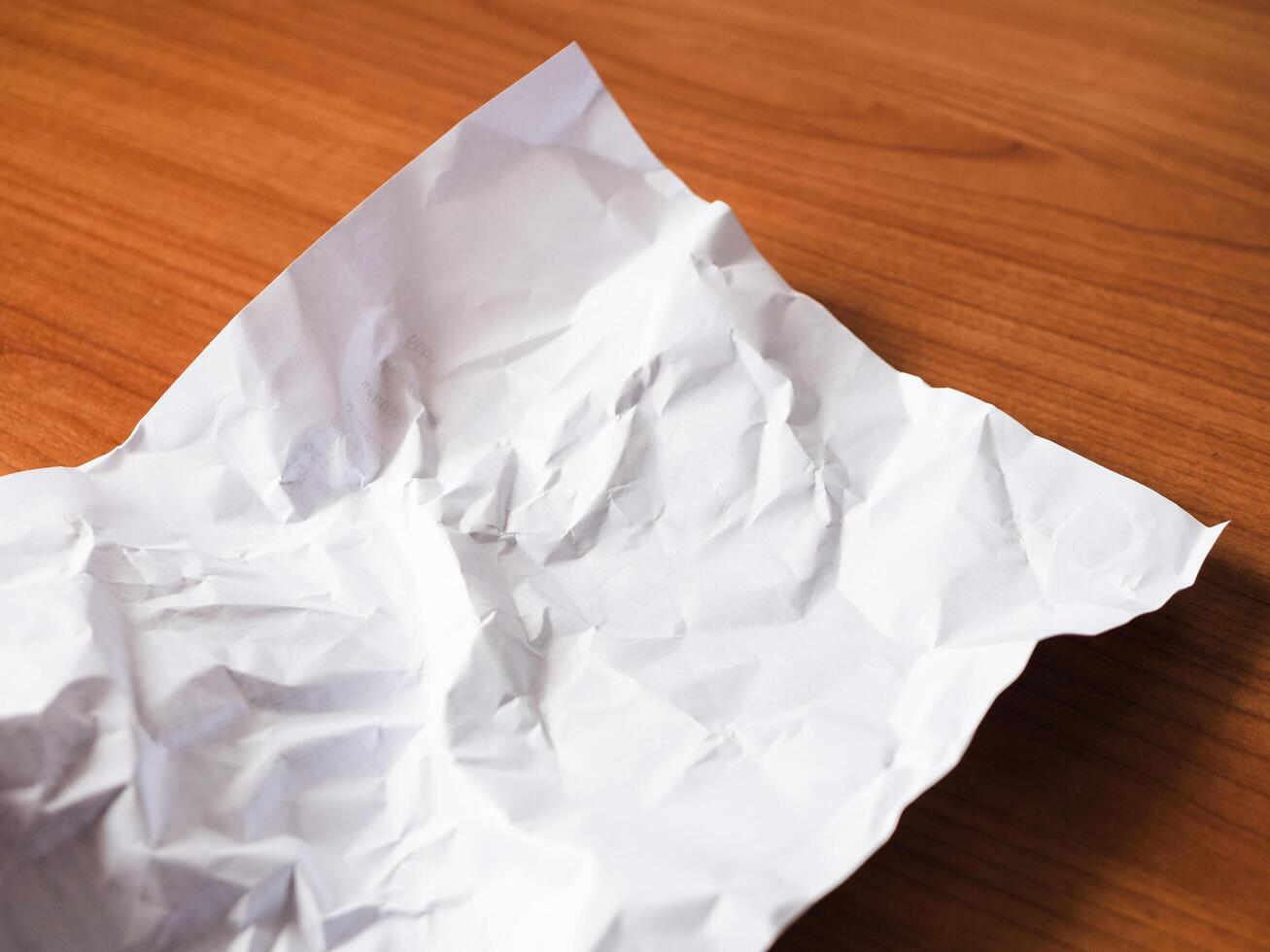 Crumpled paper wooden surface still life indoor setting close-up view textural contrast photo