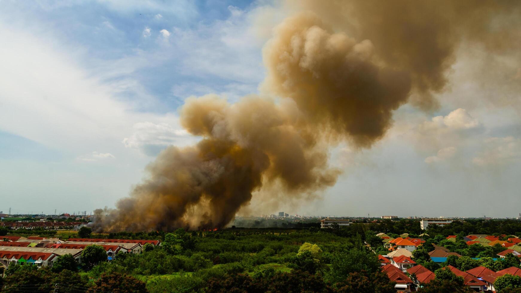 Fire incident causes heavy smoke plume over city urban landscape aerial view environmental impact photo
