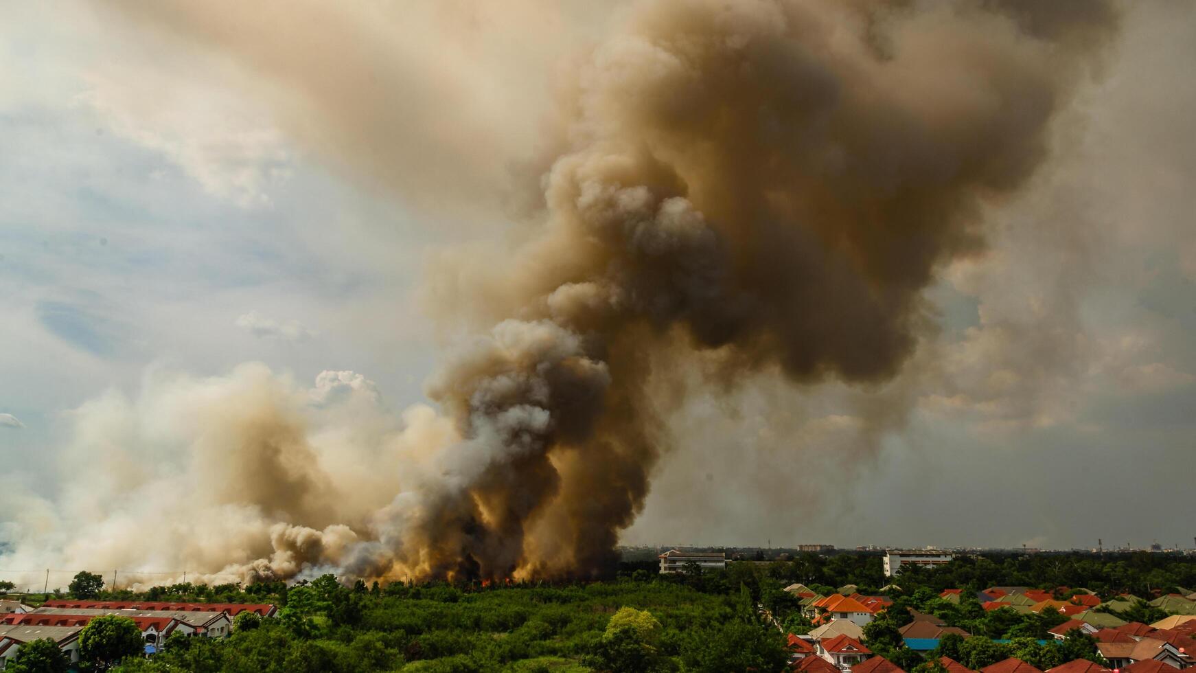 Massive smoke plume from fire incident urban area nature daytime aerial view environmental impact photo