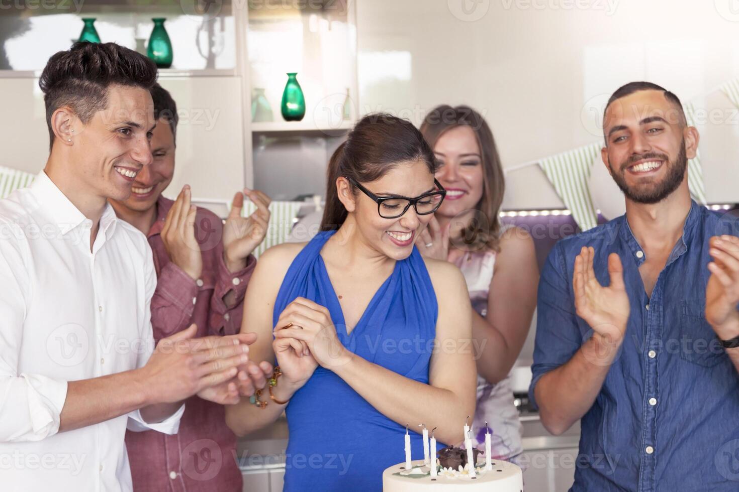 happy young woman celebrated by her friends clapping around the birthday cake photo
