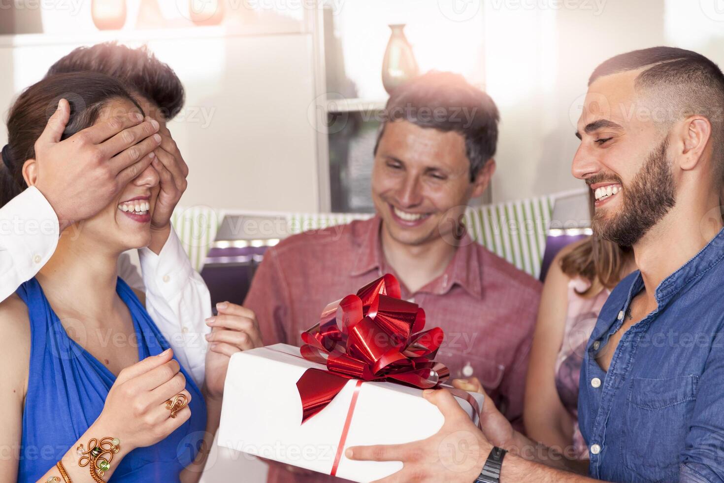 happy young woman receiving gift at birthday party from her friends photo