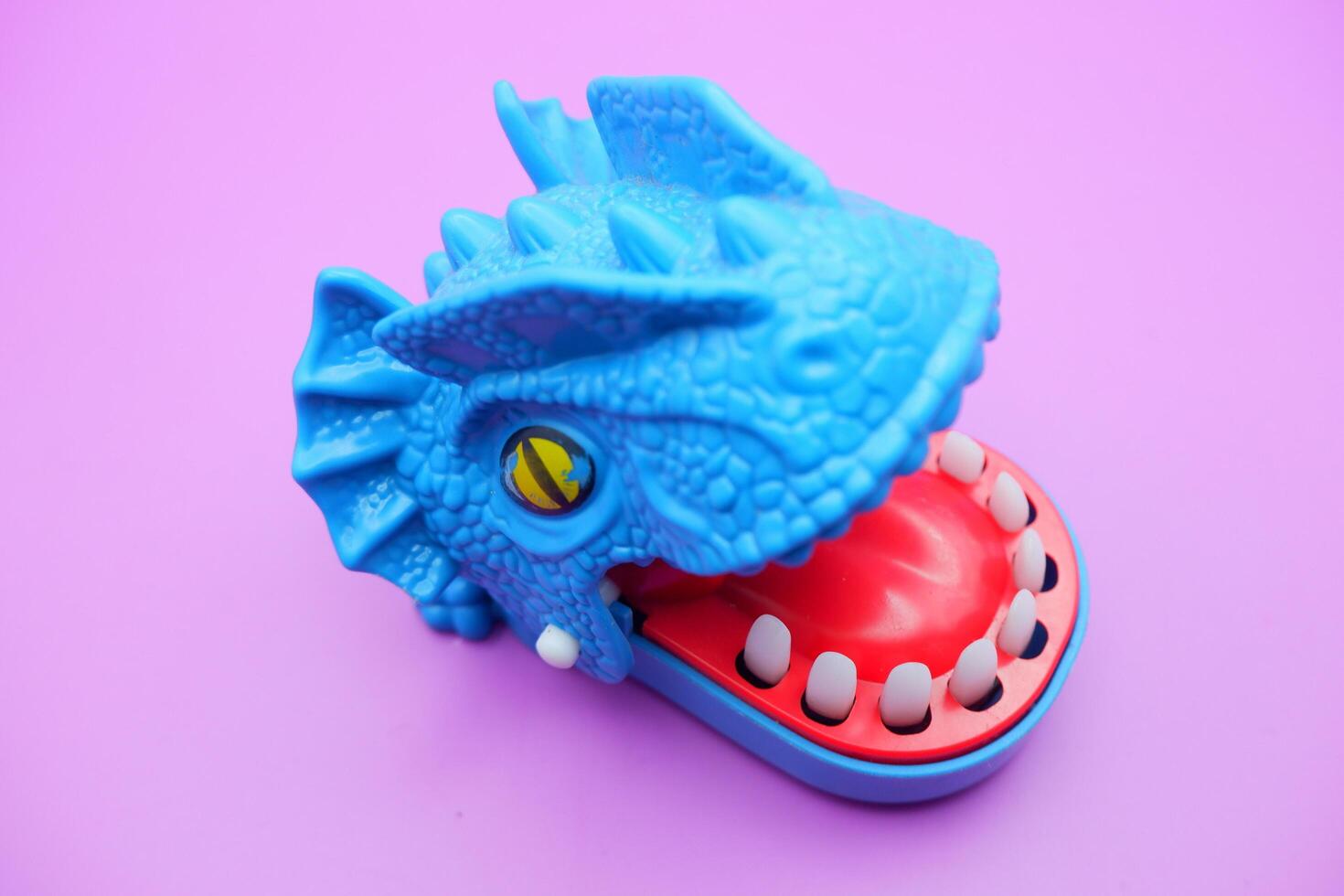 Blue Dinosaur Bite Game Toy on Pink Background photo