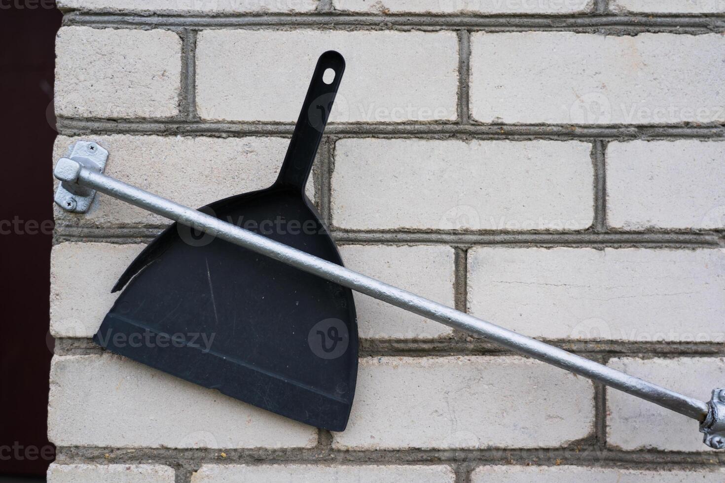 A plastic, black dustpan was stuck between the railing and the wall of the house photo